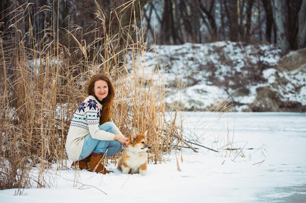 Dziewczyna i mały szczeniak puszysty ładny corgi na świeżym powietrzu. Zima