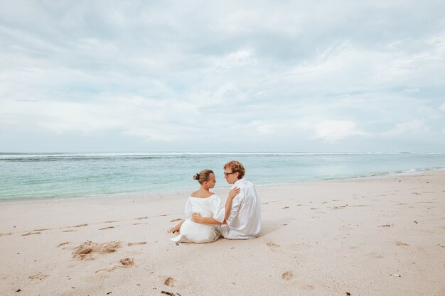Dziewczyna i mężczyzna w białych szatach na białej plaży i przytulanie