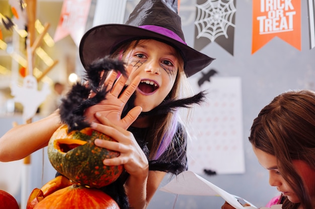 Dziewczyna i sztuczki. Ciemnooka dziewczyna ubrana w kostium czarodzieja na Halloween płata figle podczas uczęszczania na przyjęcie