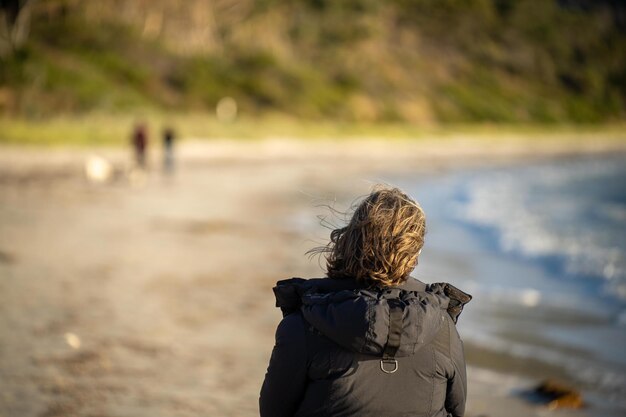 Dziewczyna idąca po molo w kurtce nad morzem