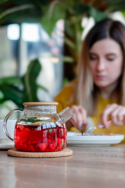 Dziewczyna je śniadanie w kawiarni Skup się na czajniczku