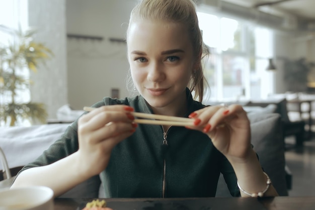 Dziewczyna Je Sushi I Bułki W Restauracji / Kuchnia Orientalna, Japońskie Jedzenie, Młoda Modelka W Restauracji