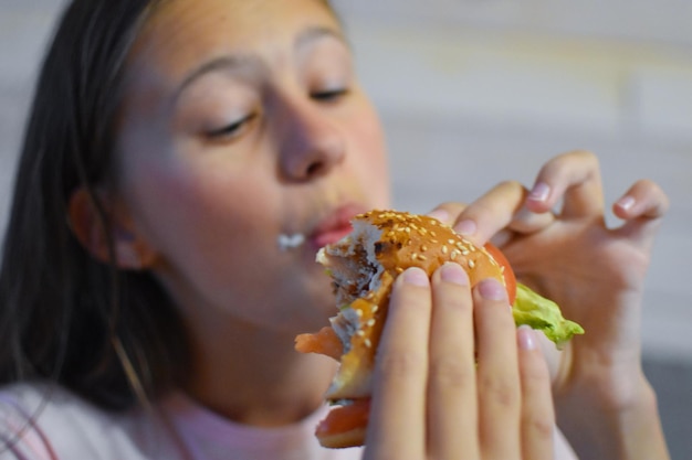 Dziewczyna jedzenie pysznego hamburgera fast food z frytkami.