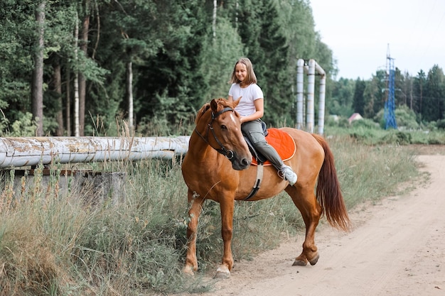 Dziewczyna jeździ konno w upalne lato w lesie