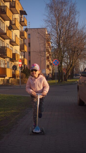 Zdjęcie dziewczyna jeździ na skuterze na ulicy przeciwko budynkom w mieście