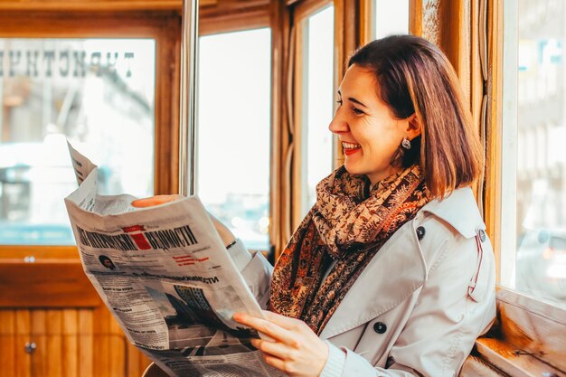 Dziewczyna jeździ naziemnym miejskim elektrycznym transportem publicznym środkiem transportu w dużym mieście pasażerka czyta wiadomości w drodze do pracy