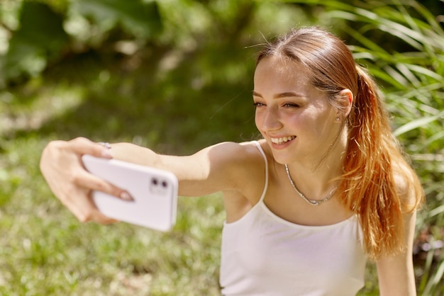 Dziewczyna komunikuje się online przez telefon w naturze na czacie online w naturze