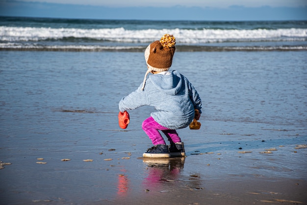 dziewczyna łapiąca wodę morską z konewką w zimie
