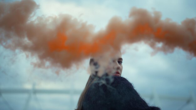 Zdjęcie dziewczyna macha ręką do kamery z bombą dymną młoda kobieta pozuje do kamery