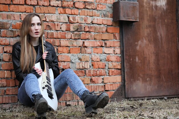 Dziewczyna muzyk rockowy w skórzanej kurtce z gitarą