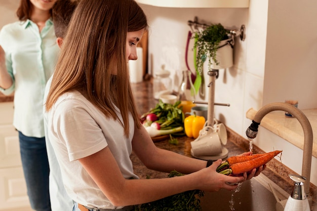 Dziewczyna mycia warzyw w kuchni w ramach przygotowań do obiadu
