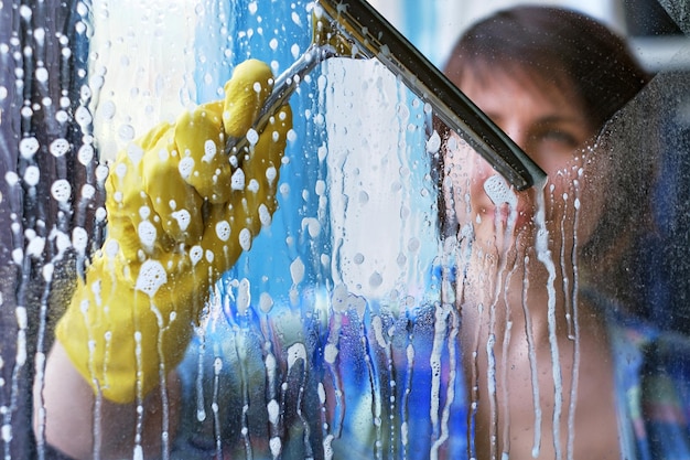 Dziewczyna myje okna w domu, żeby posprzątać dom