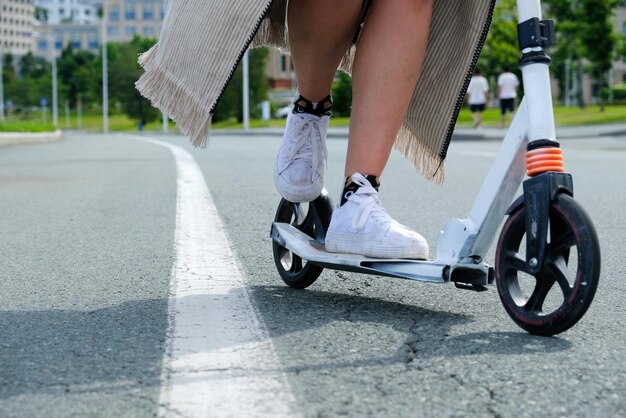 dziewczyna na hulajnodze jedzie asfaltową drogą oddzielającą pas