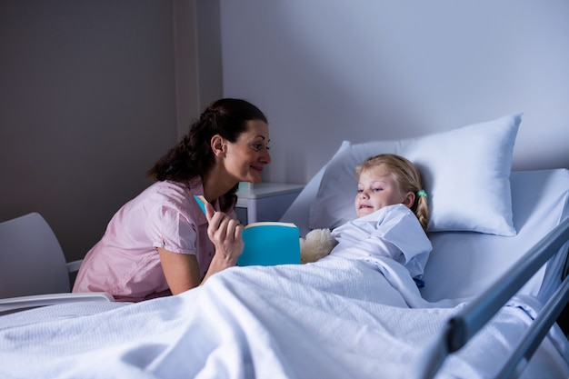 Dziewczyna na łóżku szpitalnym, czytanie książki z matką