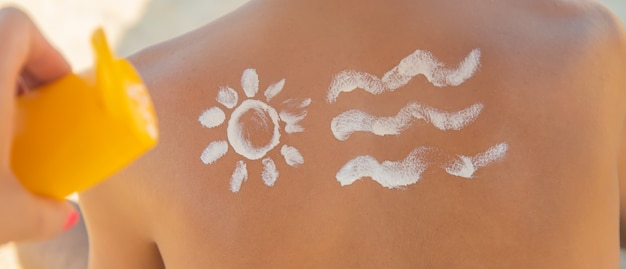 Dziewczyna na plaży nakłada krem przeciwsłoneczny na skórę mężczyzny.