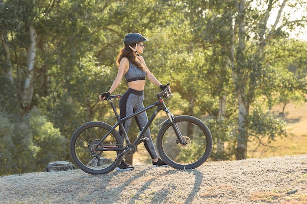 Dziewczyna na rowerze górskim na offroad piękny portret rowerzysty o zachodzie słońca Jeździ dziewczyna fitness