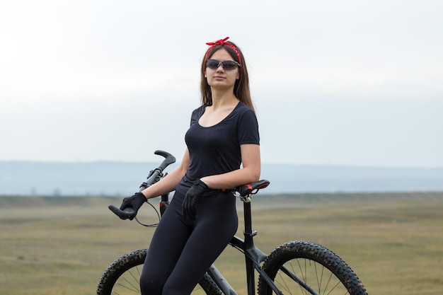 Dziewczyna Na Rowerze Górskim Na Offroad Piękny Portret Rowerzysty W Deszczową Pogodę Dziewczynka Fitness Jeździ Na Nowoczesnym Rowerze Górskim Z Włókna Węglowego W Odzieży Sportowej Portret Zbliżenie Dziewczyny W Czerwonej Chustce