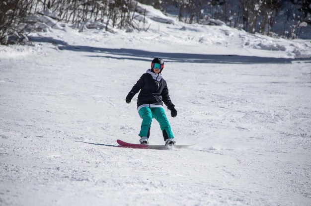 Dziewczyna na snowboardzie zjeżdża po zboczu góry