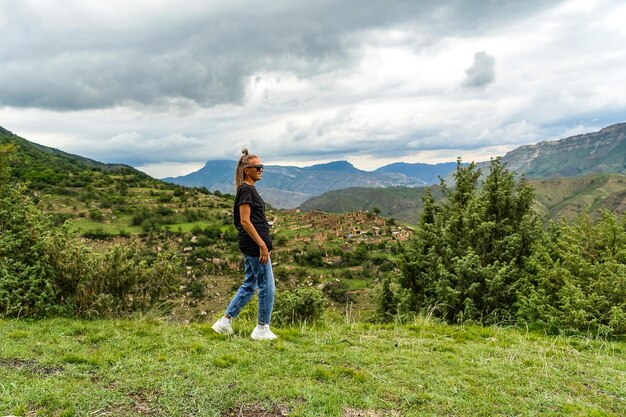 Dziewczyna na tle wsi Kurib w górach Kaukazu na szczycie klifu Dagestan Rosja czerwiec 2021