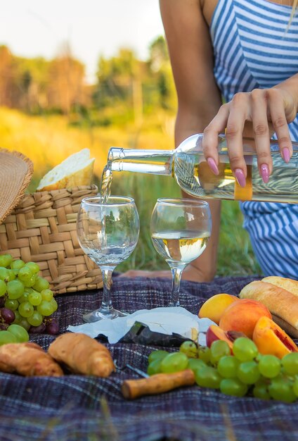 Dziewczyna nalewa wino na pikniku. Selektywne skupienie. Natura.