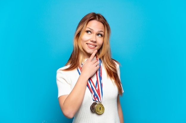 Zdjęcie dziewczyna nastolatka z medalami na pojedyncze ściany patrząc w górę podczas uśmiechu