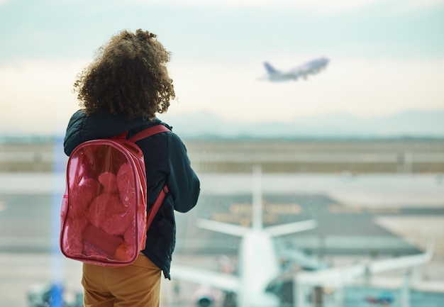 Dziewczyna patrząca na dziecko i okno lotniska na powitanie i skupienie się na międzynarodowym transporcie lotniczym lub podróży Dzieciak z powrotem i oglądanie startu przez szkło dla globalnej imigracji młodych i afrykańskich