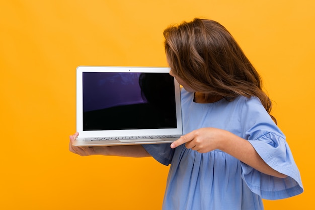 Dziewczyna patrzeje laptopu pokazu na kolor żółty ścianie