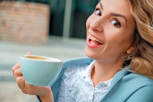 Dziewczyna pijąca kawę na ulicy filiżankę kawy filiżankę kawy i zbliżenie twarzy dziewczyny