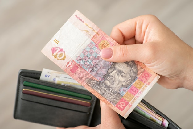 Dziewczyna płaci za swój zakup małymi ukraińskimi pieniędzmi Banknot dziesięciu hrywien w kobiecej dłoni z bliska