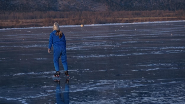 Dziewczyna pociąg na lodzie łyżwiarstwo szybkie Dziecko jeździ na łyżwach zimą w niebieskim ubraniu sportowym okulary sportowe Dzieci łyżwiarstwo szybkie sport Outdoor slow motion Ośnieżone góry piękny lód