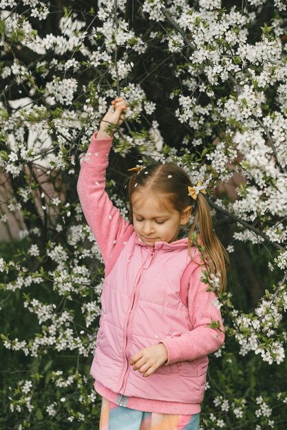 Dziewczyna pod kwiatami wiśni potrząsająca gałęziami