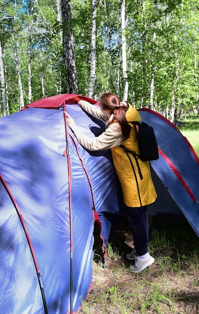 Dziewczyna podczas pobytu na łonie natury rozstawia namiot kempingowy