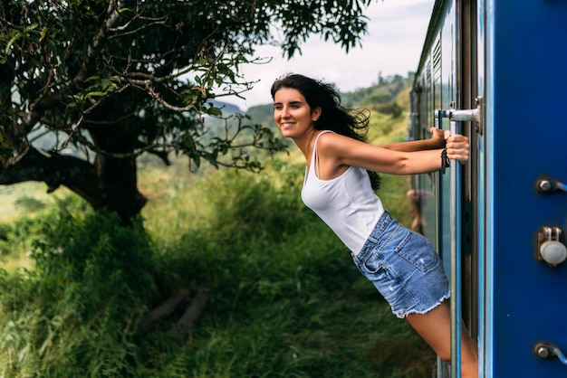 Dziewczyna podróżuje pociągiem do pięknych miejsc. Piękna dziewczyna podróżuje pociągiem wśród gór. Podróżować pociągiem. Podróż do Azji. Pociągi Sri Lanki. Transport kolejowy. Kolej żelazna. Transport Azja