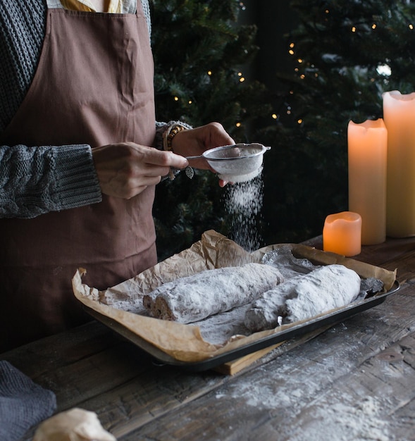 Dziewczyna posypuje świąteczny stollen cukrem pudrem