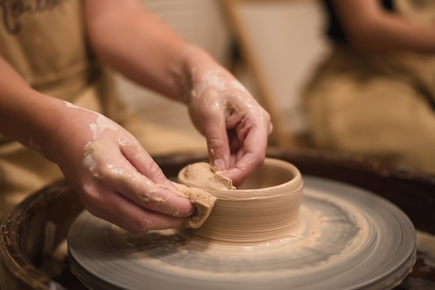 Dziewczyna Pottera pracuje na kole garncarskim, wykonując ceramiczny garnek z gliny w warsztacie garncarskim. Koncepcja sztuki i hobby