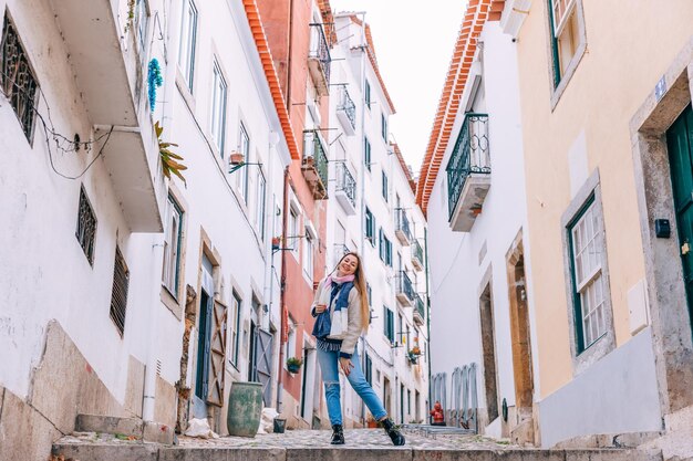 Dziewczyna pozująca między budynkami na wąskiej ulicy w Lizbonie