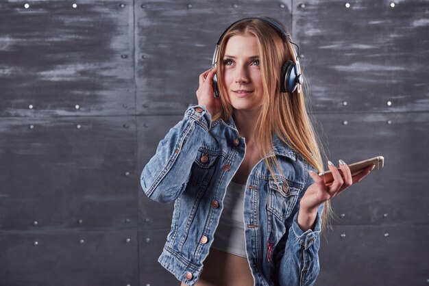 Dziewczyna pozuje w studio słucha muzyki w słuchawkach