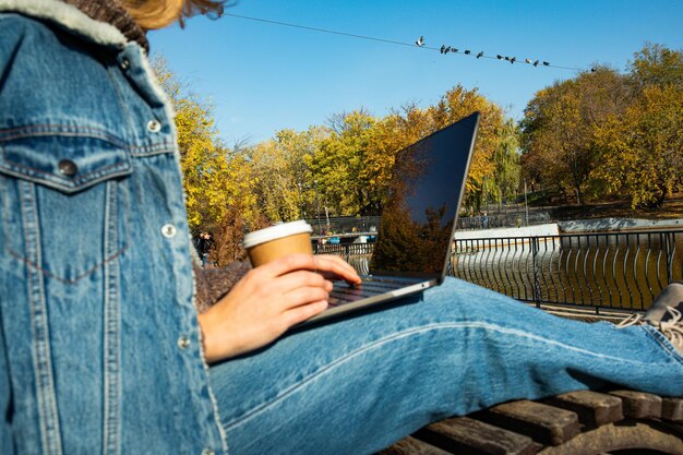 Zdjęcie dziewczyna pracuje przy laptopie w parku jesieniowym