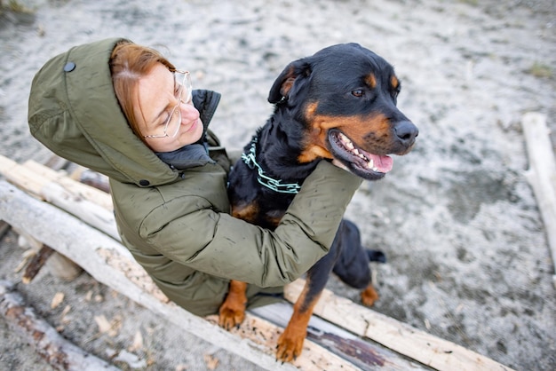 Dziewczyna przytulająca psa Rottweilera na plaży