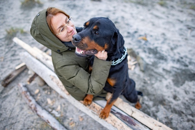 Dziewczyna przytulająca psa Rottweilera na plaży