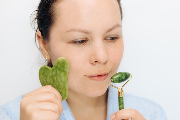 Dziewczyna robi masaż jadeitowym masażerem zbliżenie problematyczna skóra