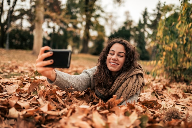 Dziewczyna robi selfie w autum parku.