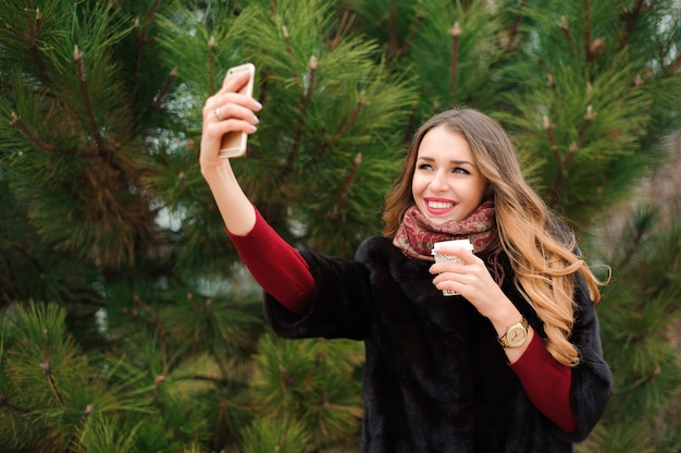 Dziewczyna robi selfie w jesień parku plenerowym