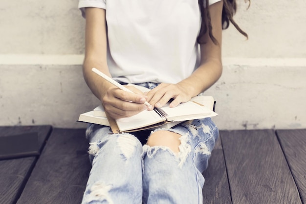 Dziewczyna robiąca notatki w pamiętniku i siedząca na drewnianej podłodze