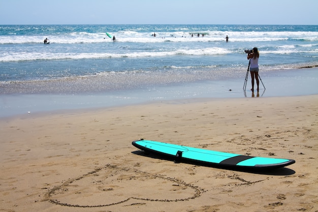 Dziewczyna robienia zdjęć dla początkujących surferów deska surfingowa na plaży i duże serce narysowane w piasku na Bali