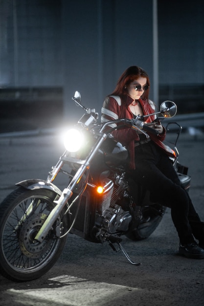 Dziewczyna rowerzysta seksualnie pozuje na motocyklu w nocy miasto