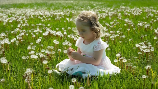 Dziewczyna siedząca na polu na wiosennej trawie z kwiatami mączka