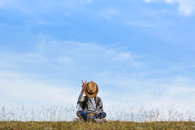 Zdjęcie dziewczyna siedząca na trawiastym polu na niebieskim niebie