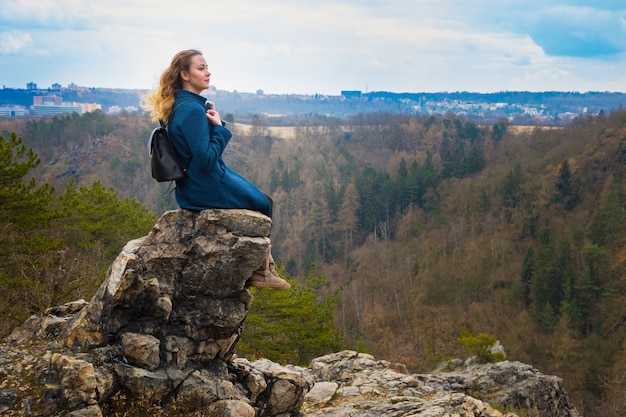 Dziewczyna siedzi na skale w górach