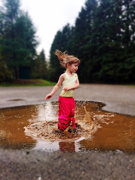 Zdjęcie dziewczyna skacząca w kałuży błotnistej